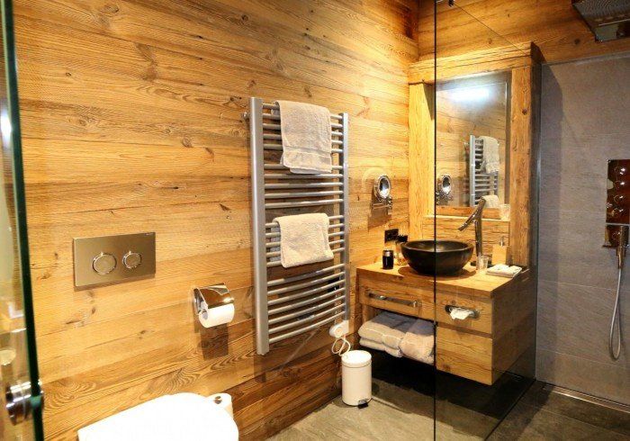 Wood-paneled bathroom with sink vanity, towel rack, toilet, and glass shower enclosure