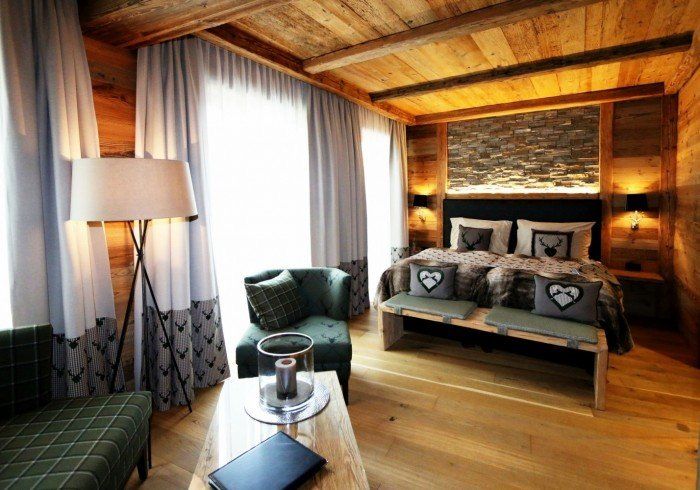 Cozy wooden bedroom with large window, bed, armchair, and floor lamp in warm light
