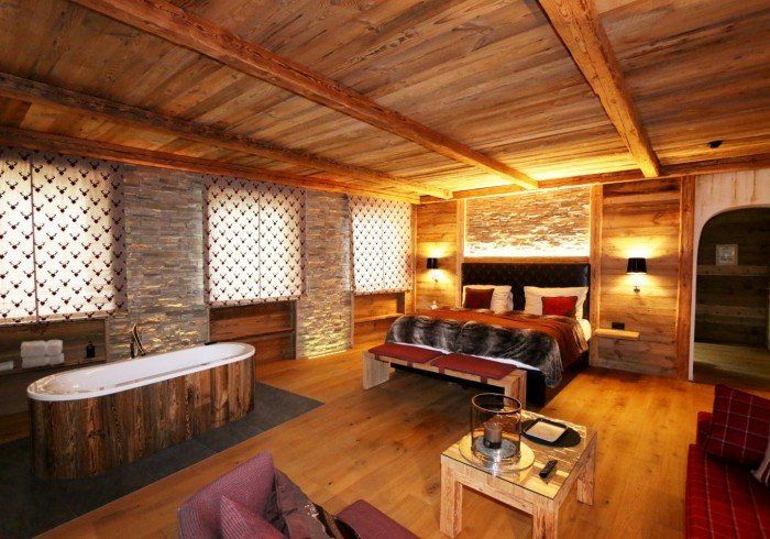 Rustic wooden spa room with hot tub, massage table, and warm ambient lighting