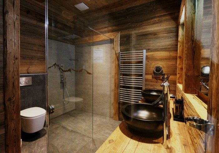 Modern bathroom with glass shower, wall-mounted toilet, and wood-paneled walls