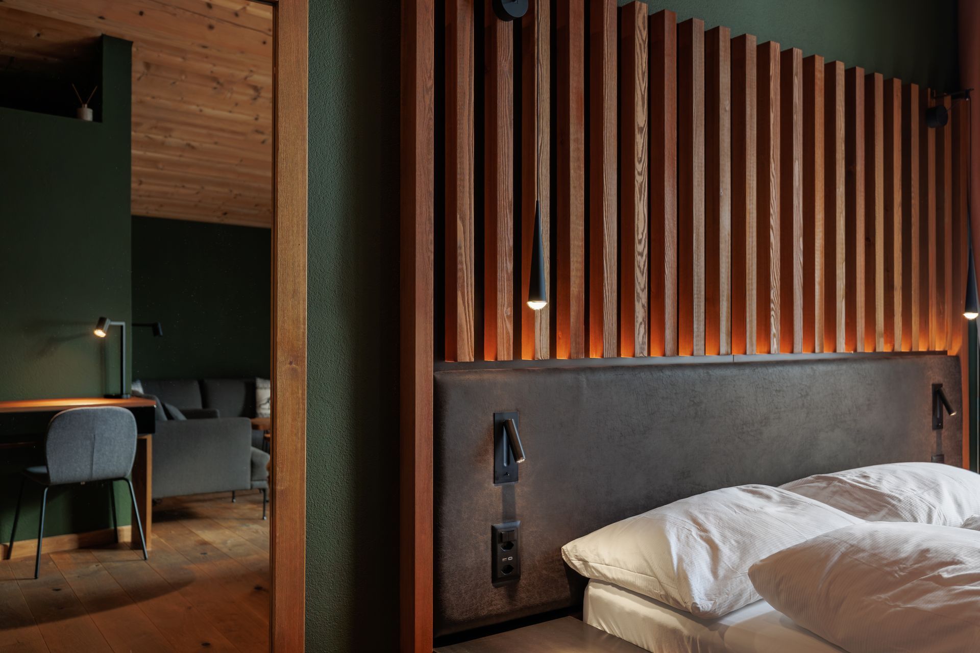 Modern bedroom with wood slat wall, dark headboard, and bed beside an open entryway