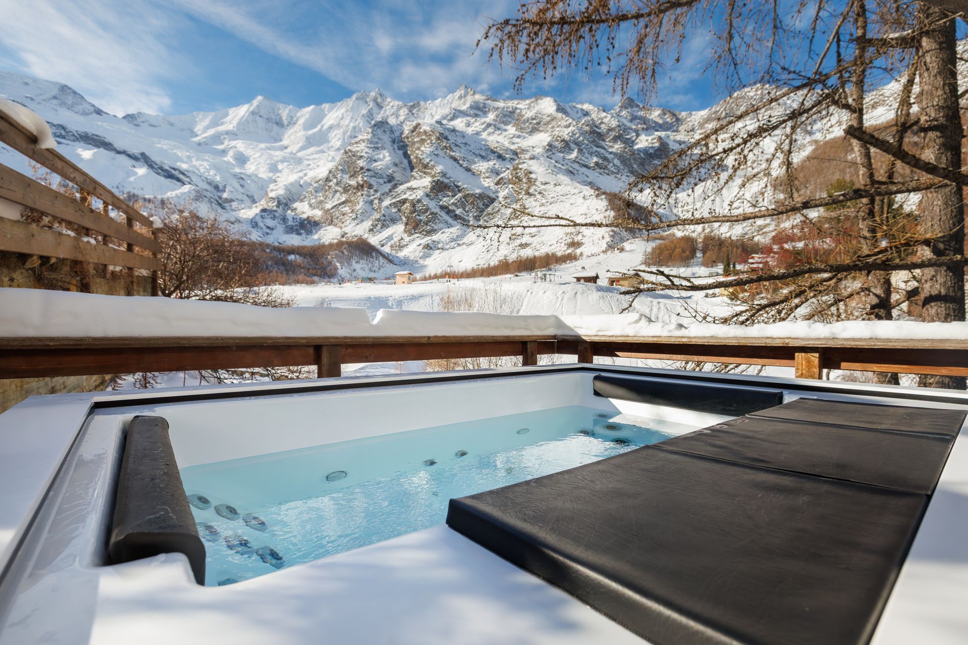 Snowy mountain hot tub with lounge chairs and a scenic alpine view