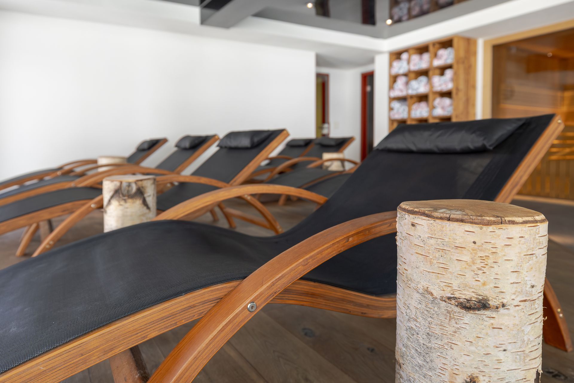 Modern spa lounge chairs with black cushions and wooden frames in a bright interior