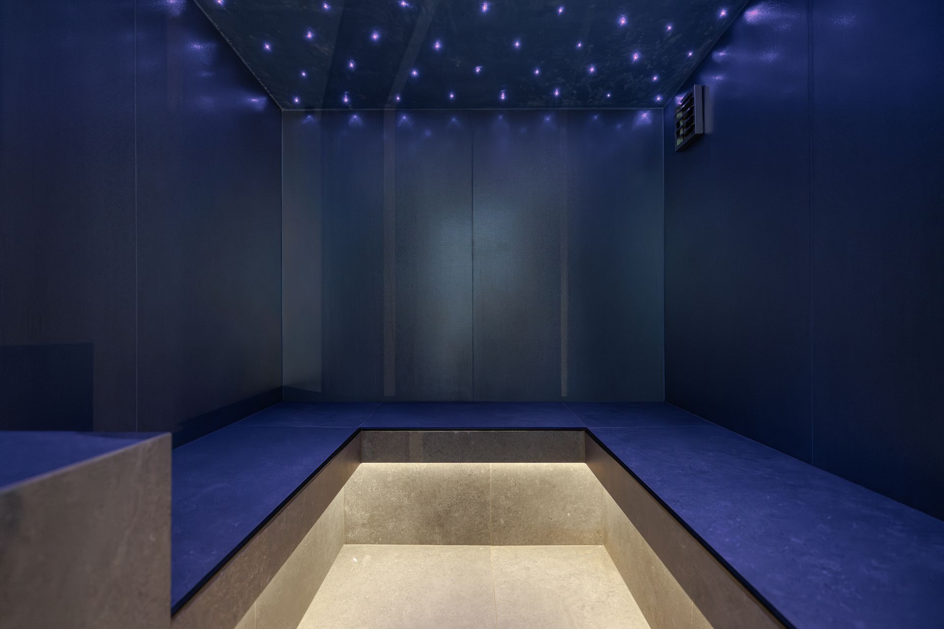 Modern blue room with star-like ceiling lights and a sunken square alcove in the center