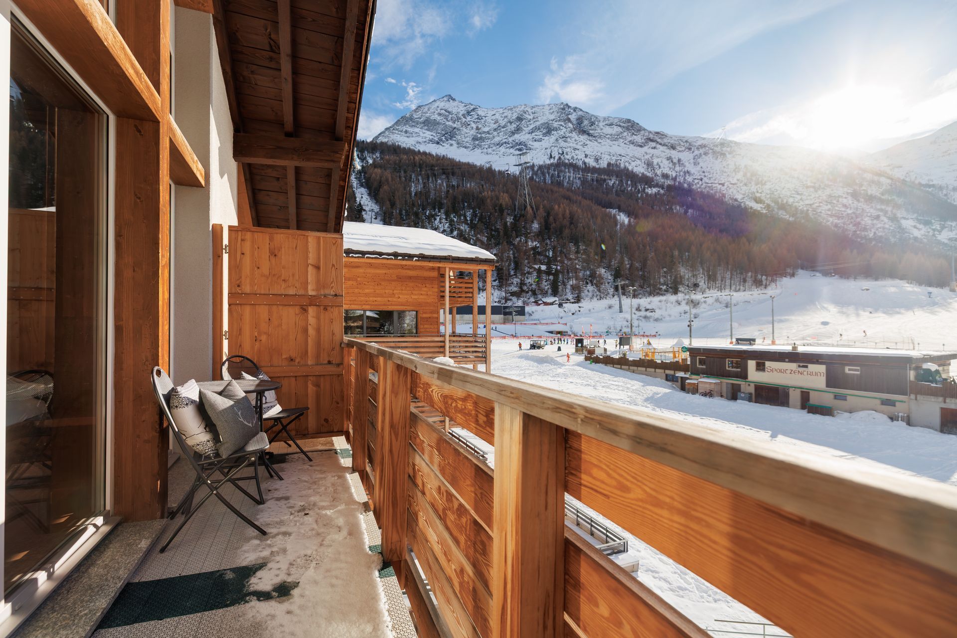 Wooden balcony overlooking snowy mountains and a bright winter valley