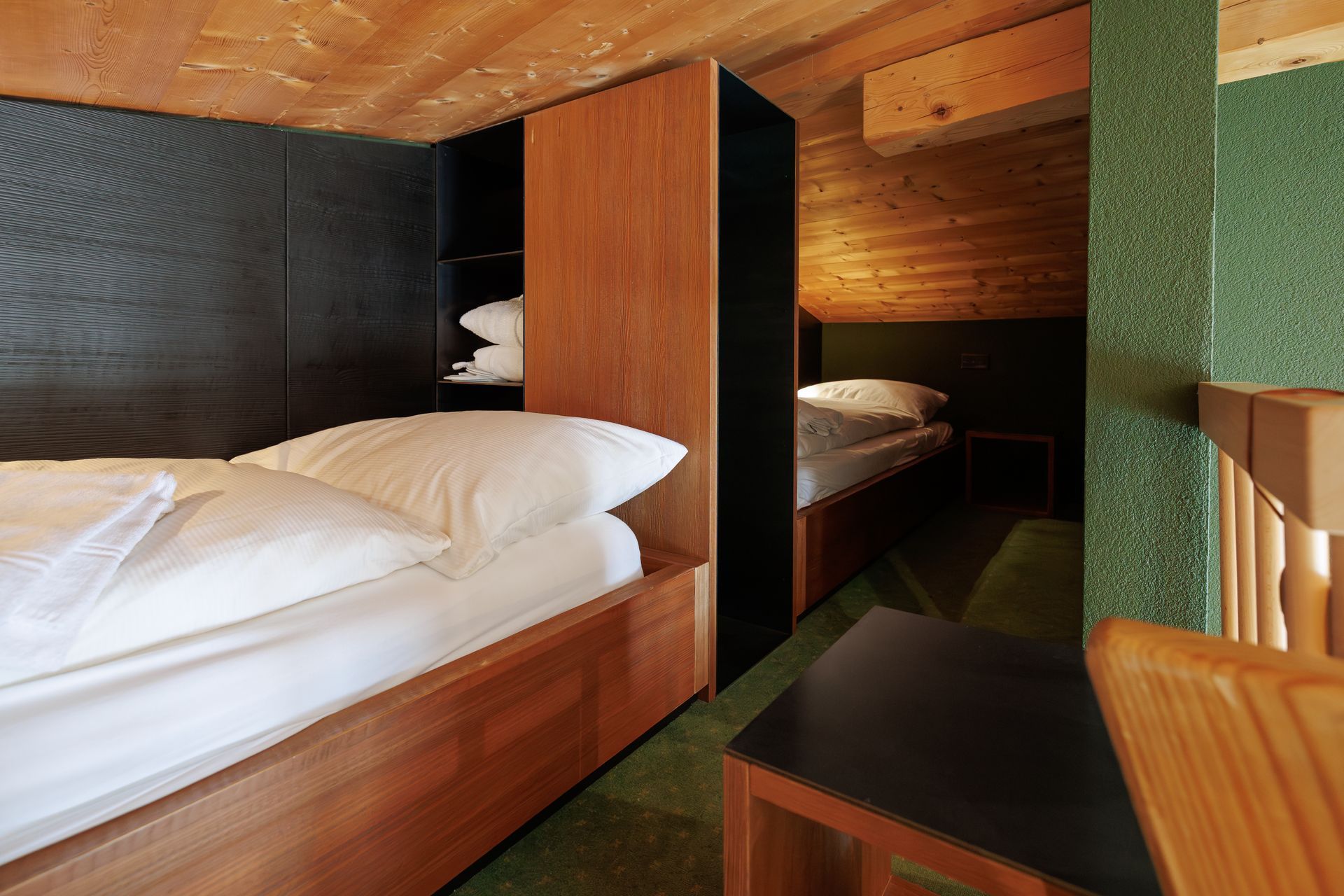Compact wood-paneled cabin bedroom with two beds and a small table