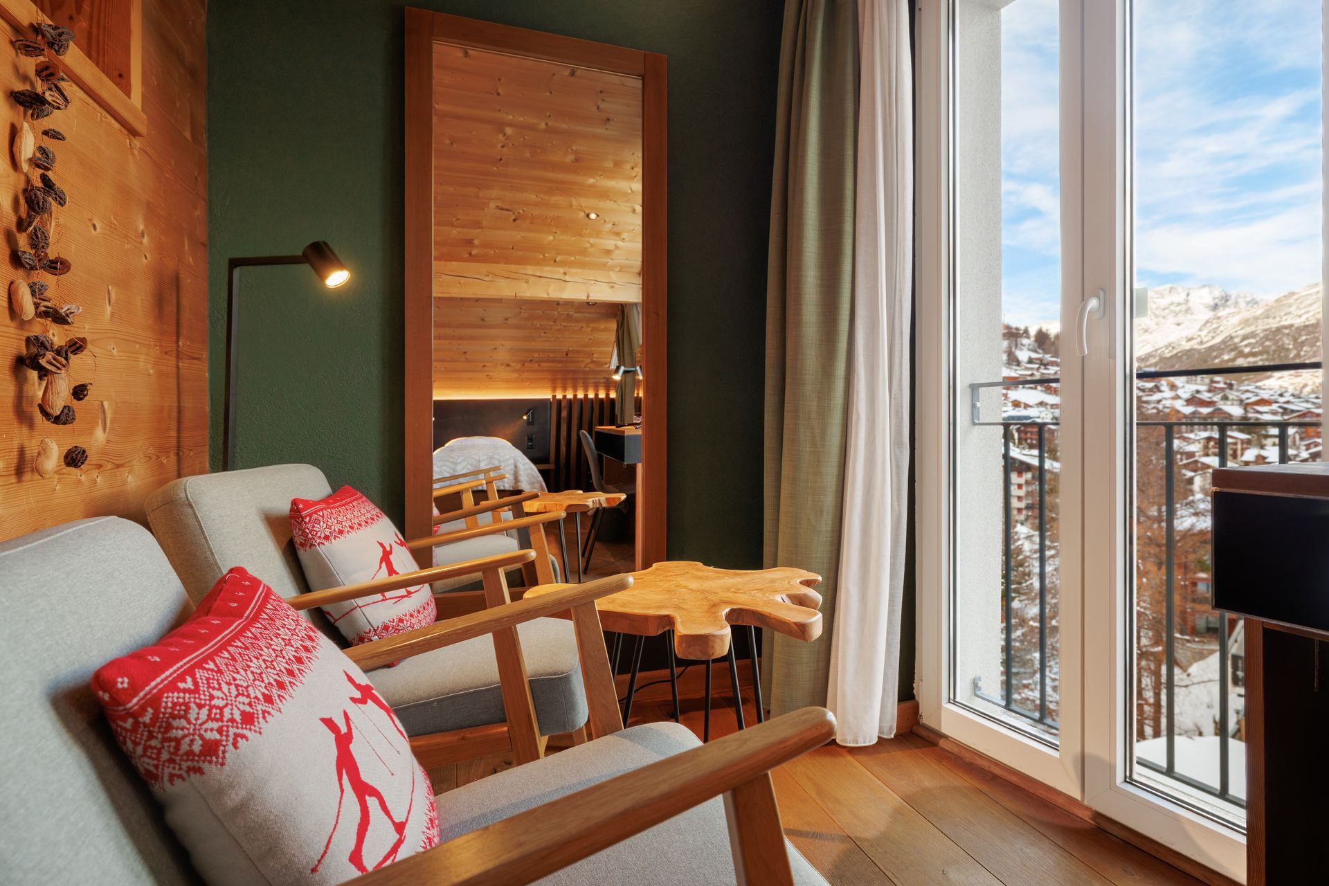 Cozy living room with red pillows, wood accents, and a balcony view through tall windows