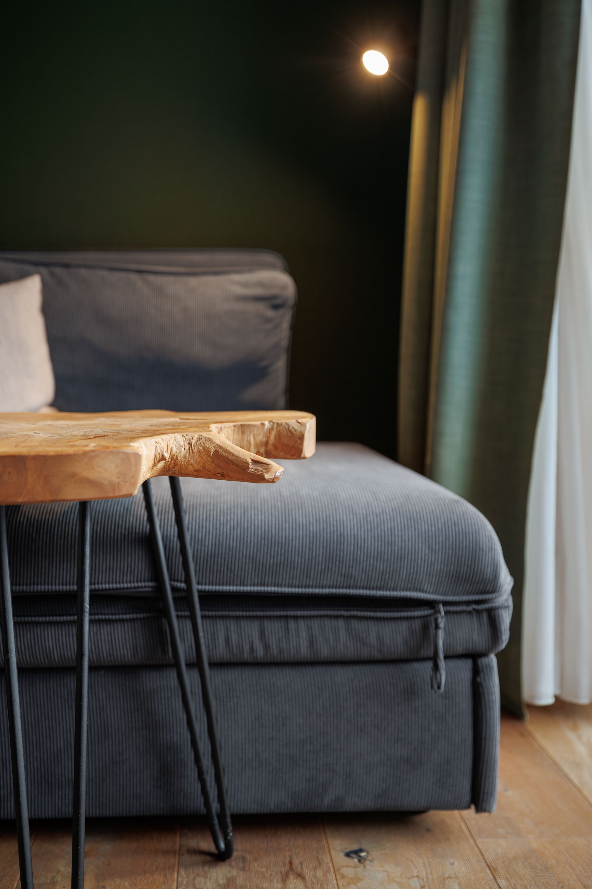 Cozy bedroom corner with a gray bed, wooden tray table, and curtains by a moonlit window