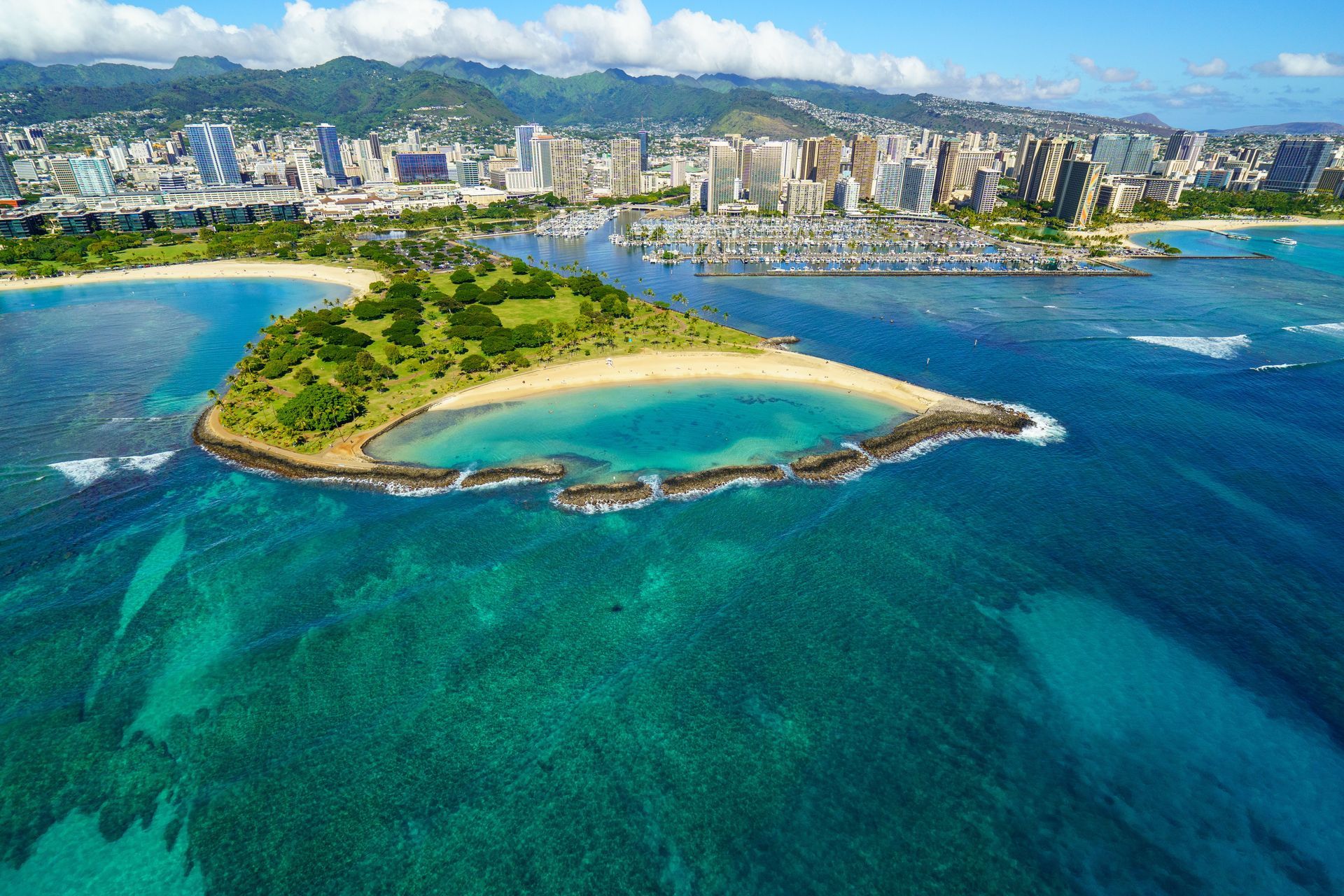 Aerial view of a tropical island with turquoise water and a city skyline in the background