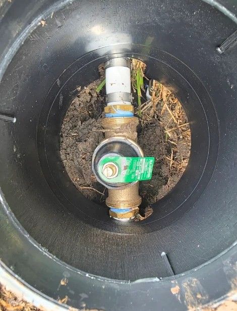 Water valve inside a black utility box, with brass fittings and a green shutoff handle.