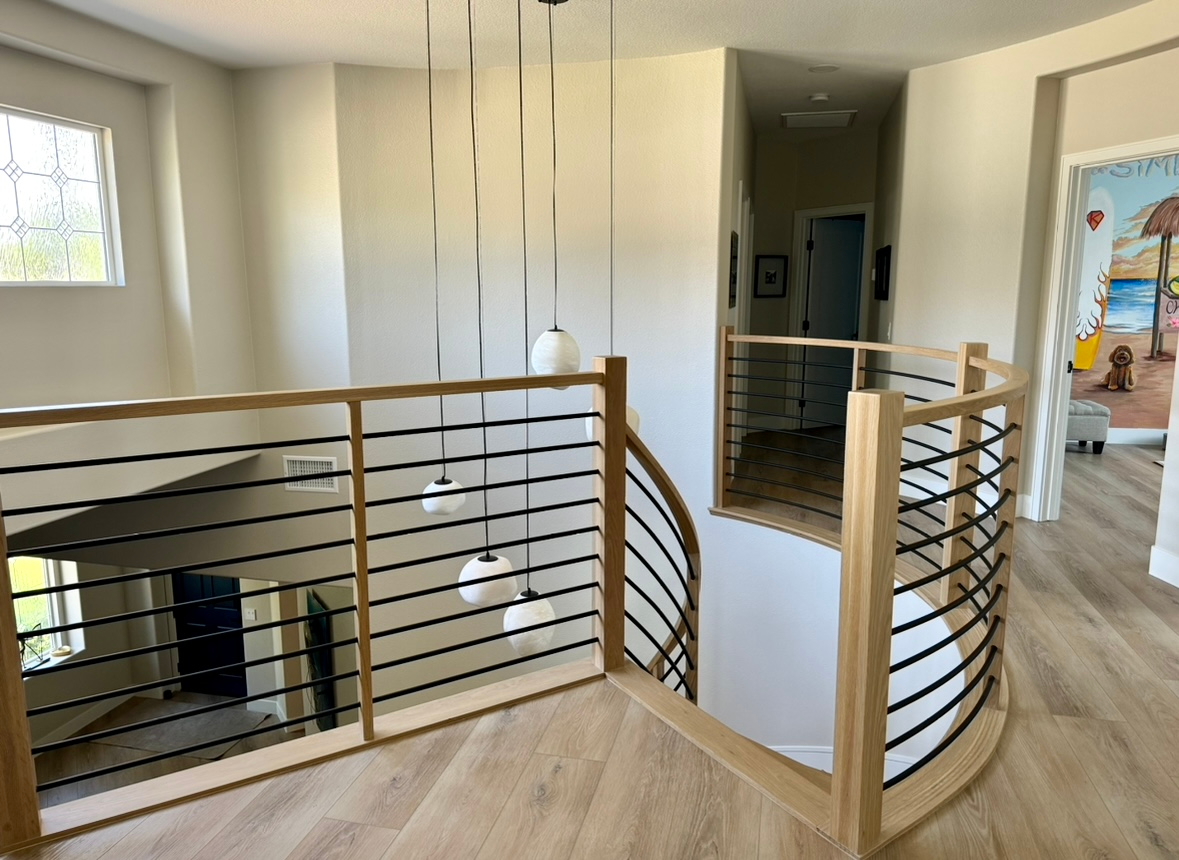 A wooden staircase with a black railing in a house.