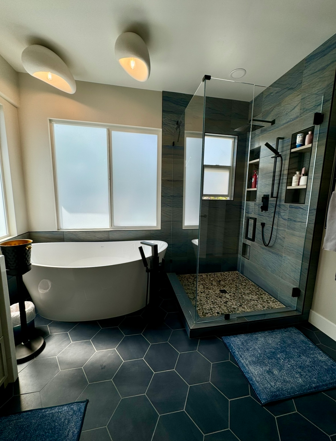 A bathroom with two sinks , two mirrors and a walk in shower.