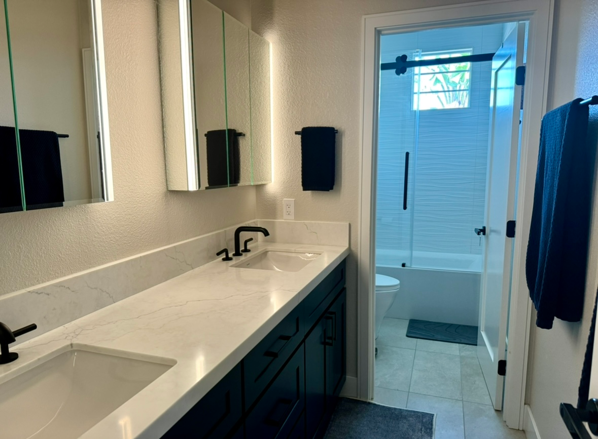 A bathroom with two sinks and a walk in shower.