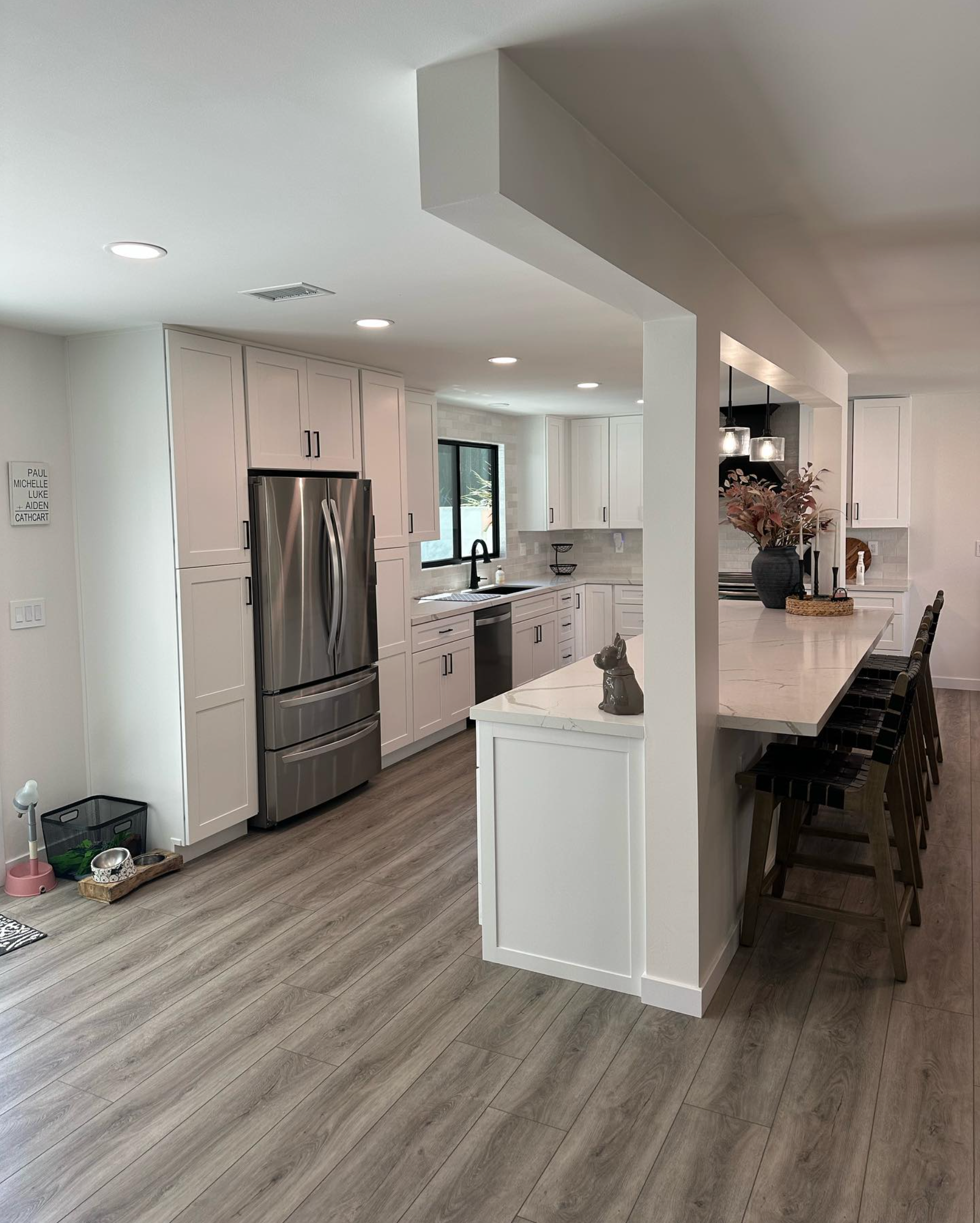 A kitchen with stainless steel appliances , a refrigerator , a table and chairs.