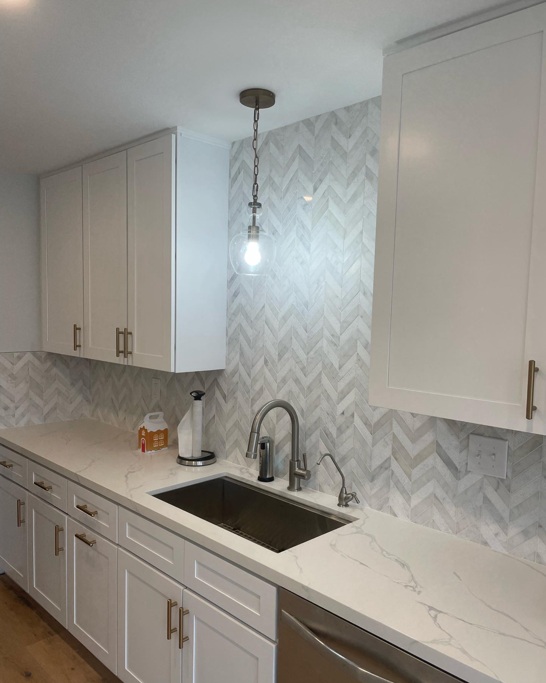 A kitchen with white cabinets , a sink , and a stainless steel dishwasher.