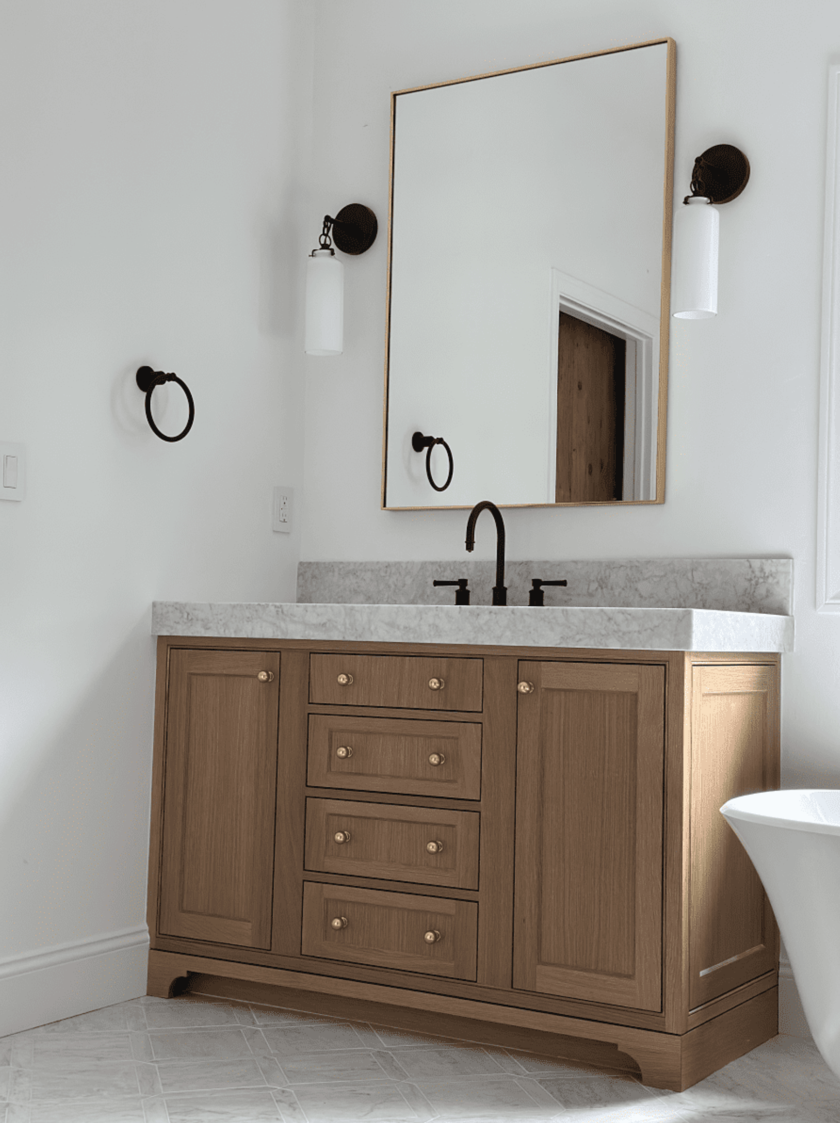 A bathroom with a wooden vanity , sink , mirror and tub.