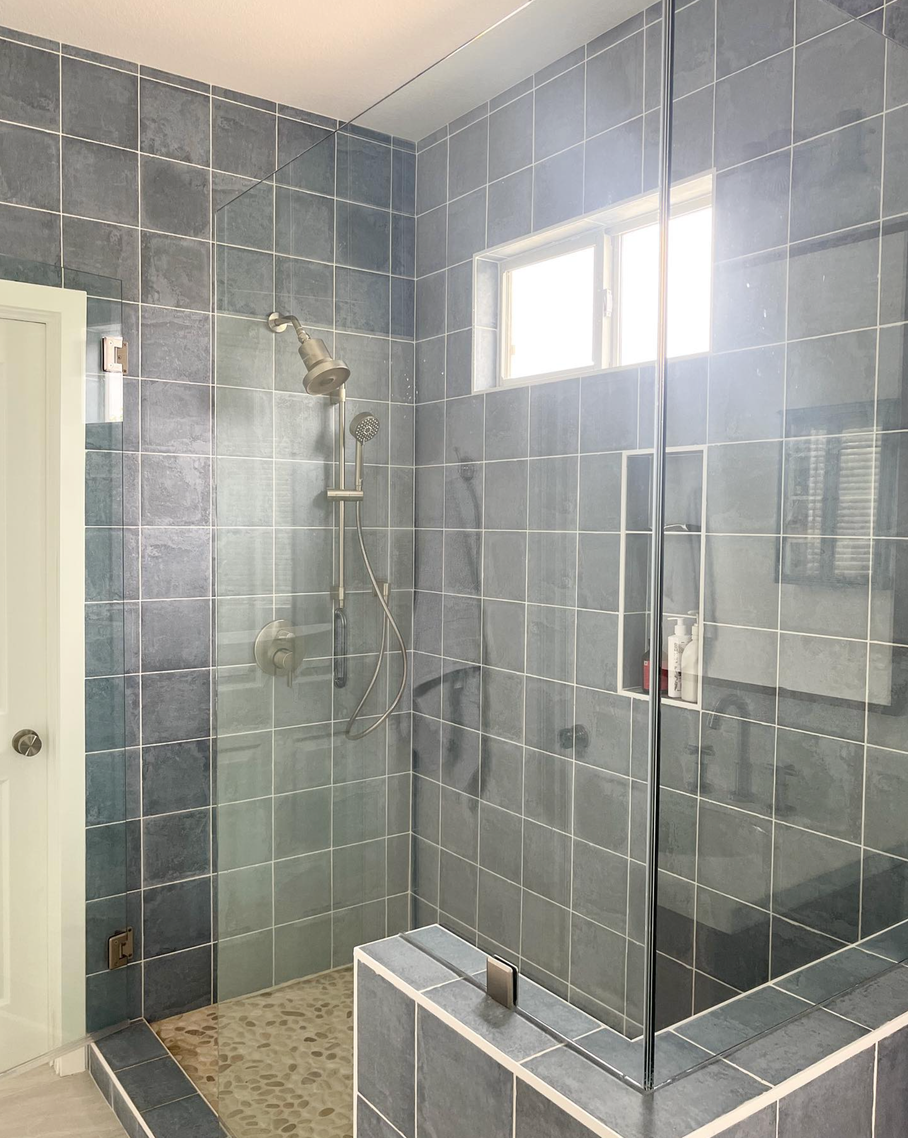 A bathroom with a walk in shower with a glass door.