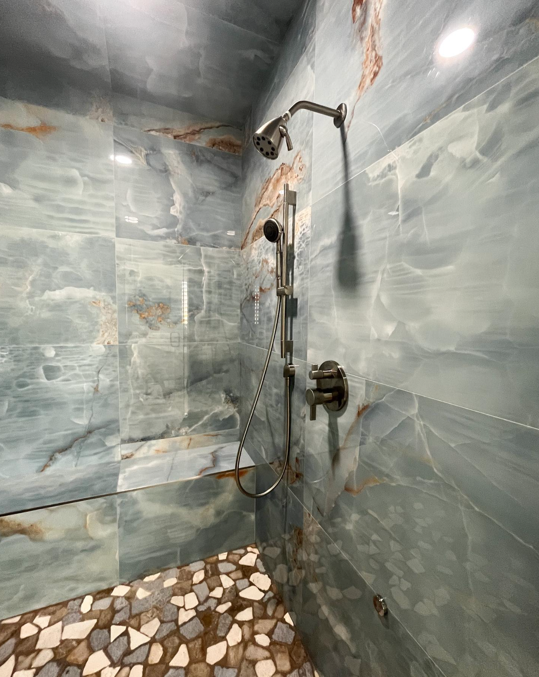 A shower with a shower head and a tiled floor.