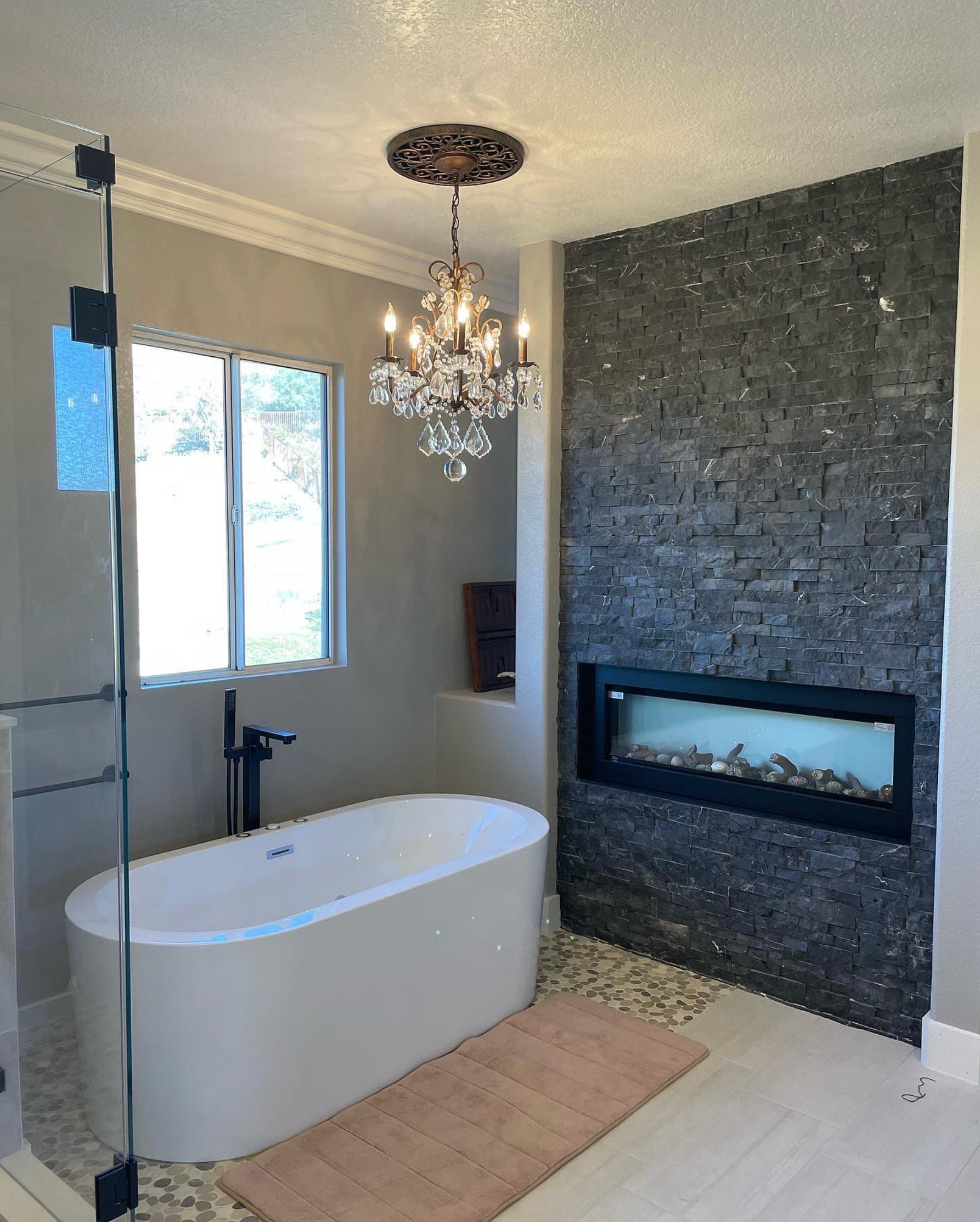 A bathroom with a bathtub , fireplace and chandelier.
