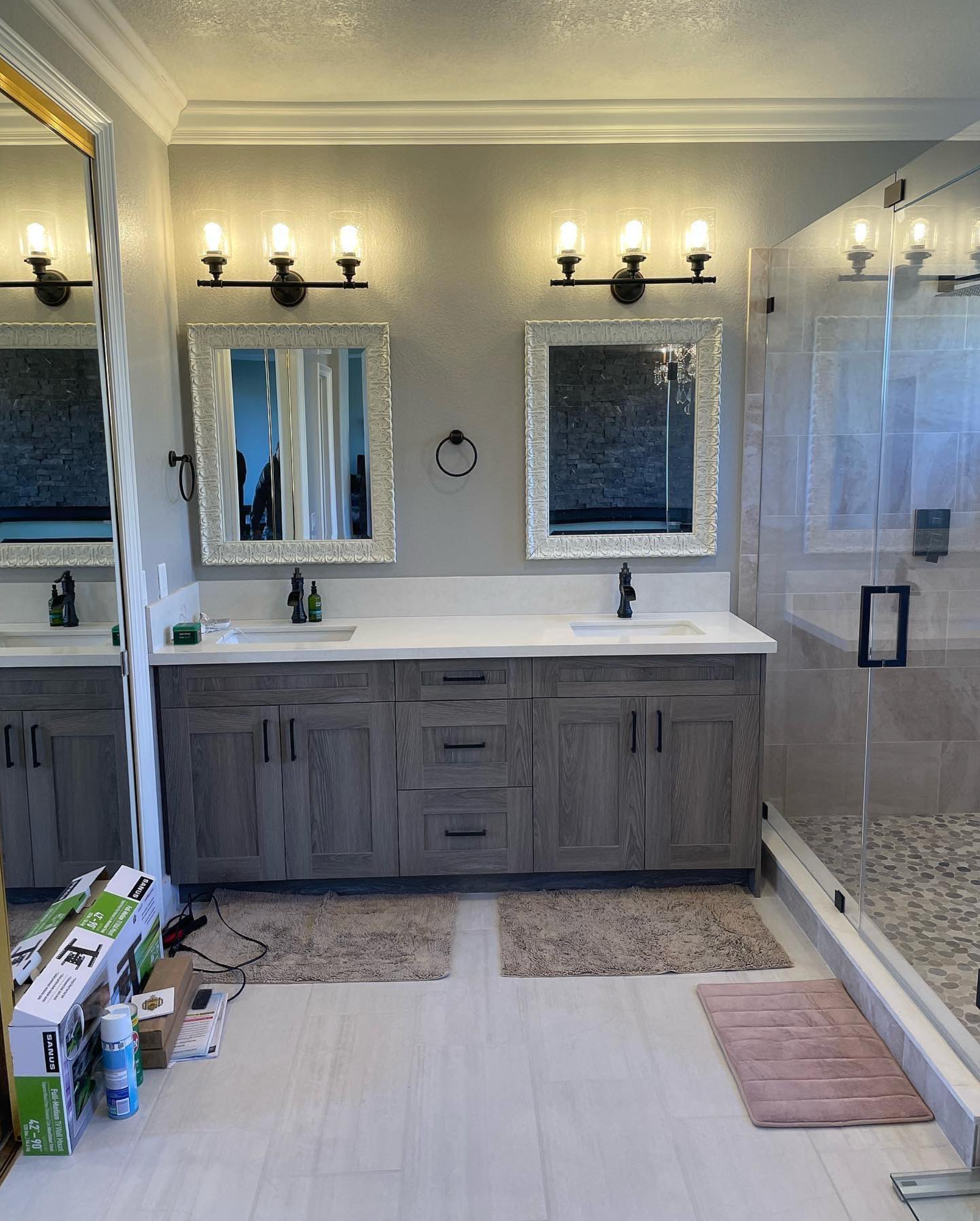 A bathroom with two sinks , two mirrors and a walk in shower.