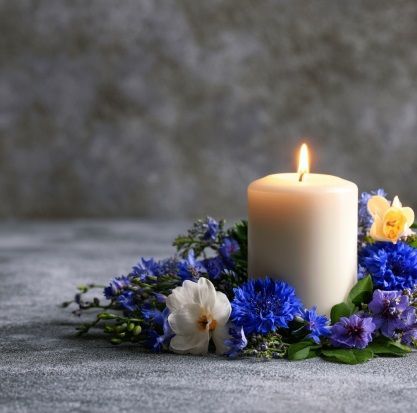 Memorial candle and blue flowers representing cremation services in Grafton, WI.