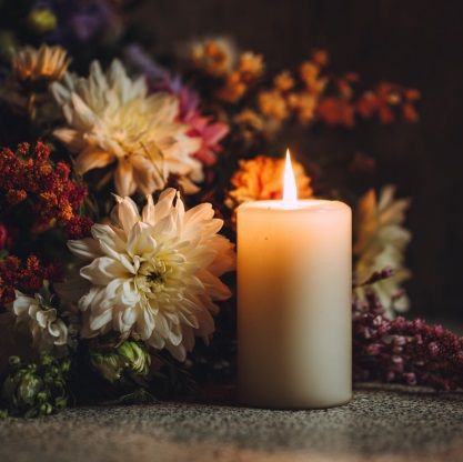 Memorial candle among flowers representing funeral homes in Port Washington, WI.