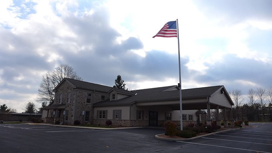 Exterior view of a welcoming funeral home building with an American flag and peaceful landscaped surroundings