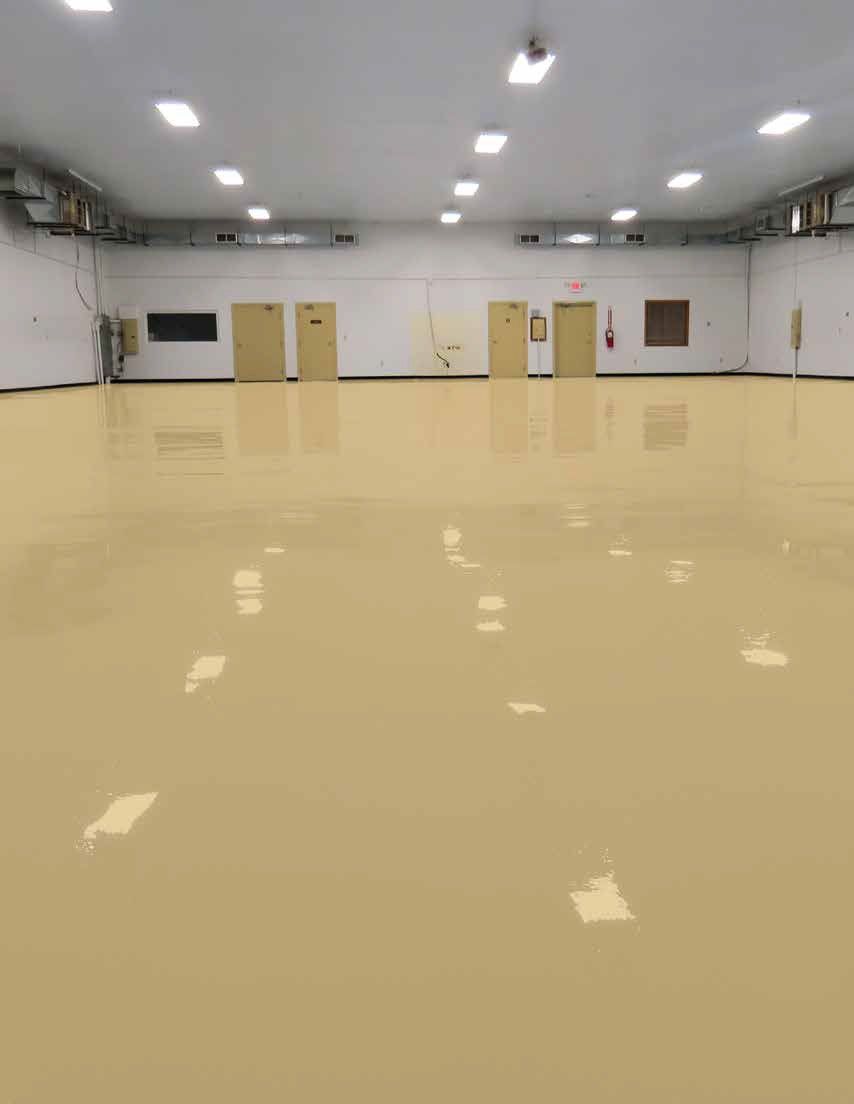 Empty indoor hall with beige floor, white walls, and overhead fluorescent lights