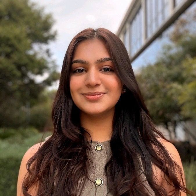 A young woman wearing a black shirt and a necklace is smiling for the camera.