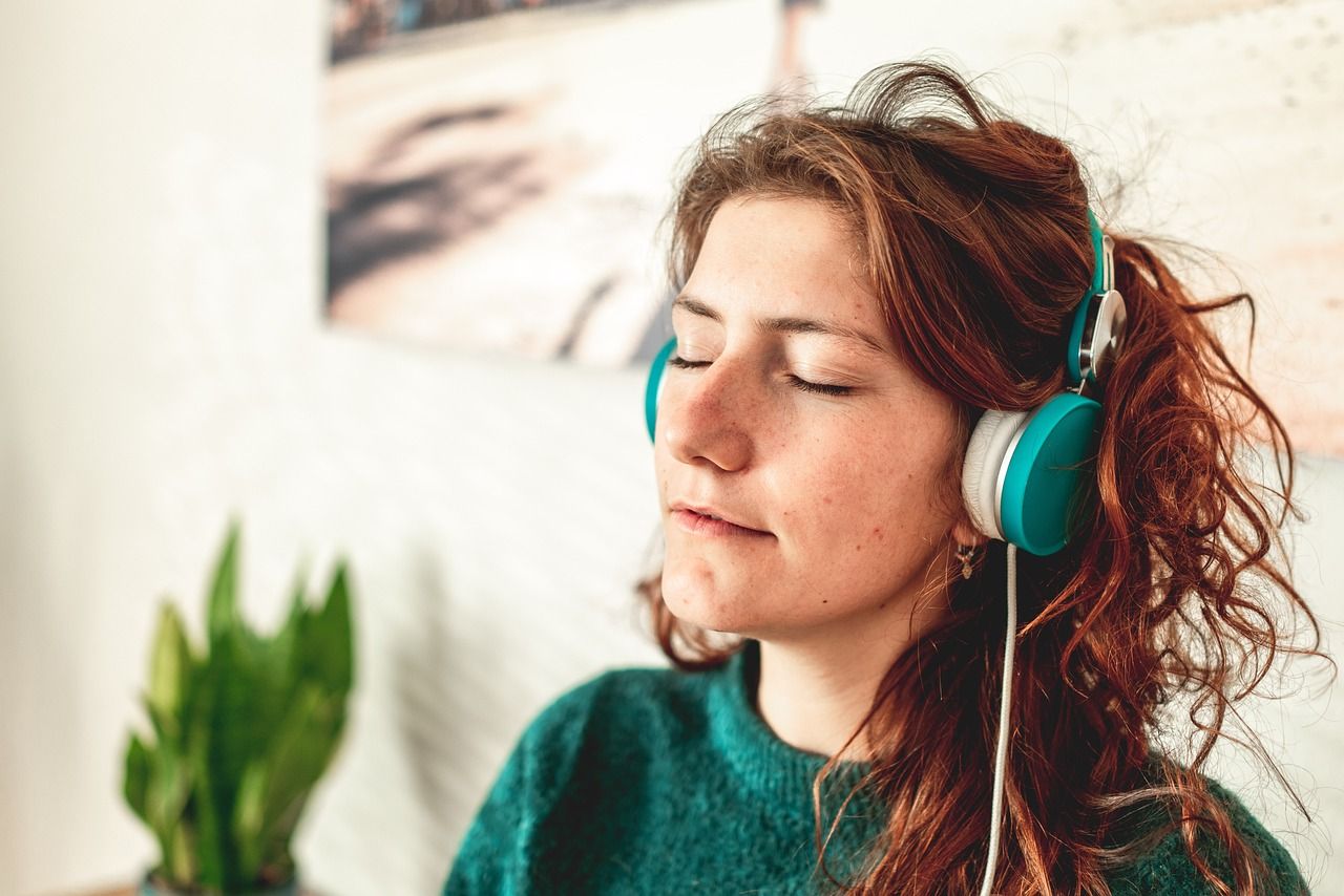 A woman wearing headphones is listening to music with her eyes closed. SIL – Supported Independent Living, NDIS, Canberra