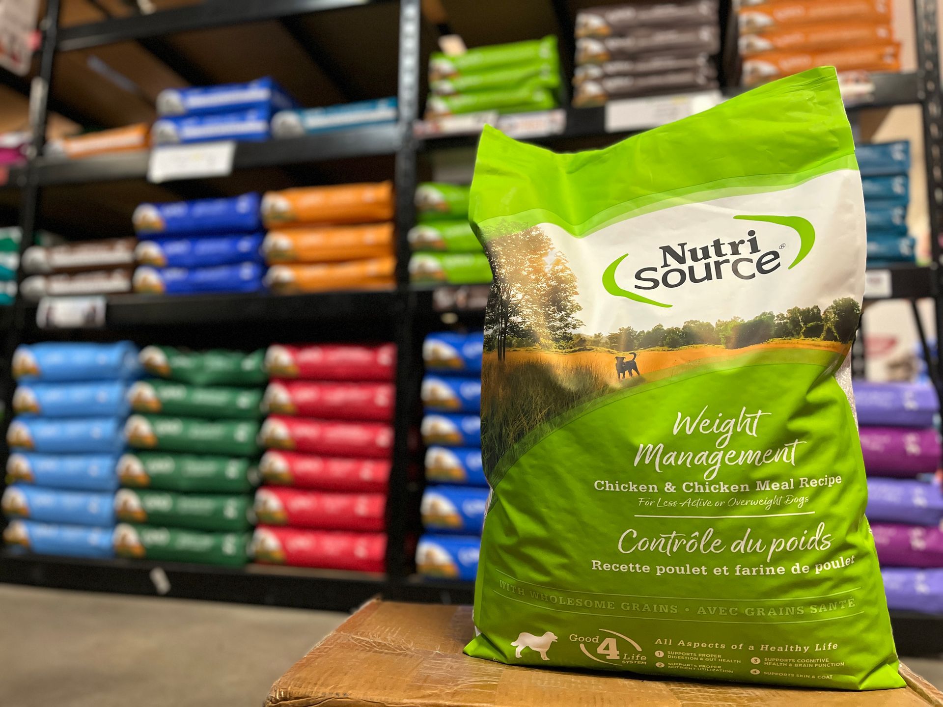 A bag of nutri source weight management dog food is sitting on a box in a store.