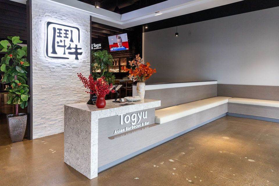 Modern hotel lobby reception desk with flowers, gray walls, and a wall logo display