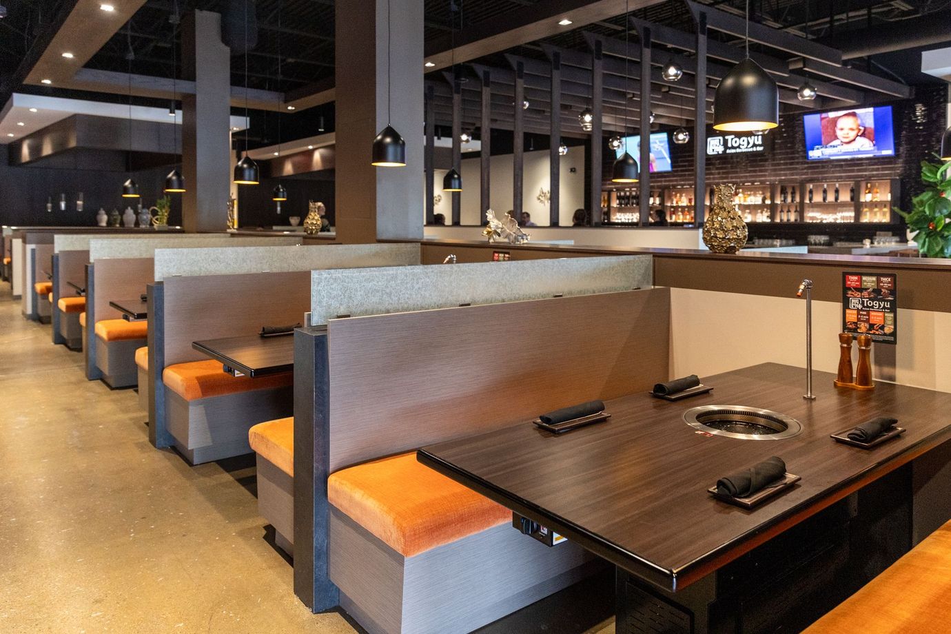 Empty restaurant booths with dark tables and orange seats in a modern dining area
