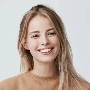 A woman with long blonde hair is smiling and wearing a brown sweater.