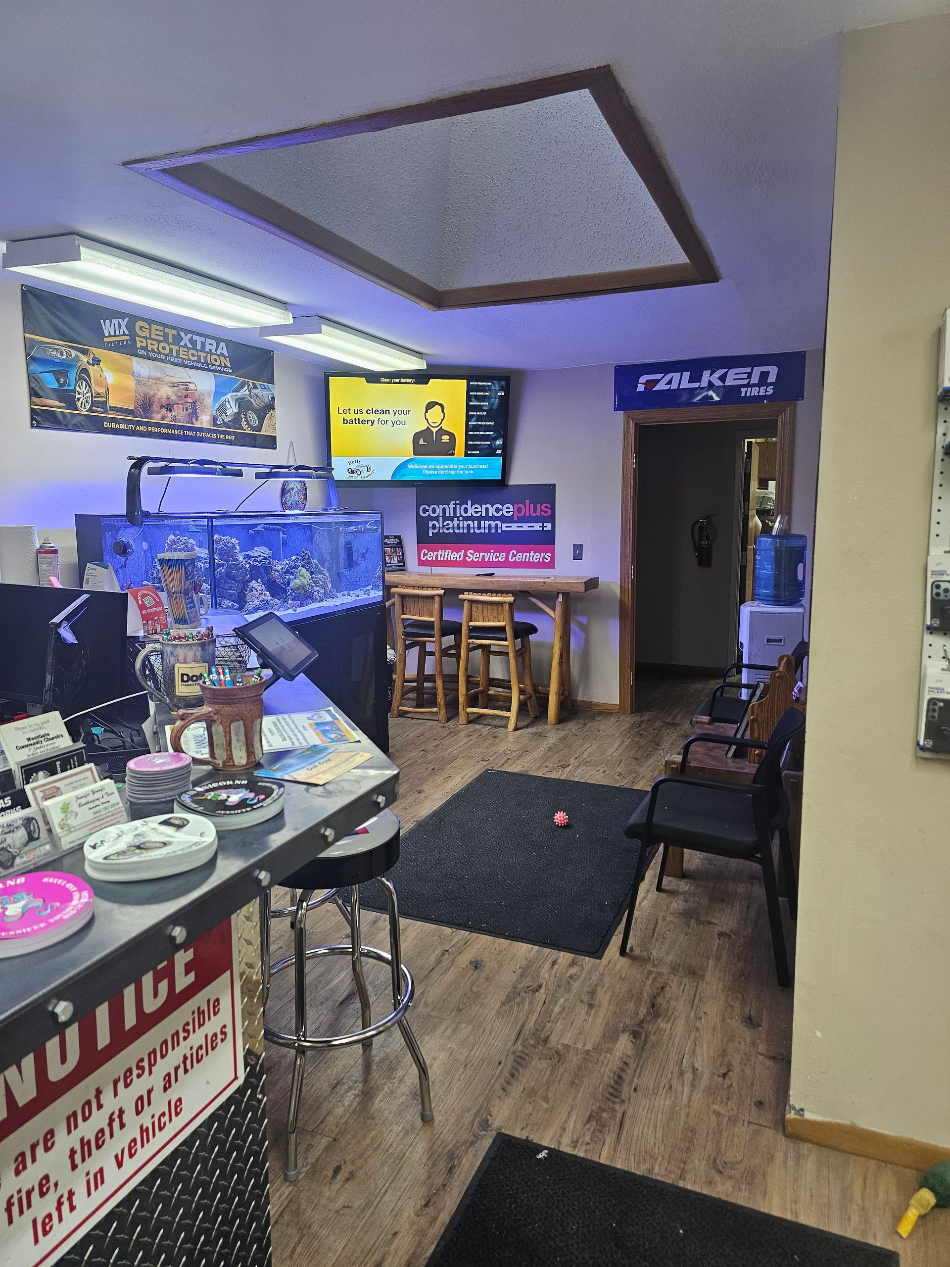 Cozy indoor café with bar counter, stools, chairs, TV screens, and warm yellow lighting | Belly Brothers Auto Tech