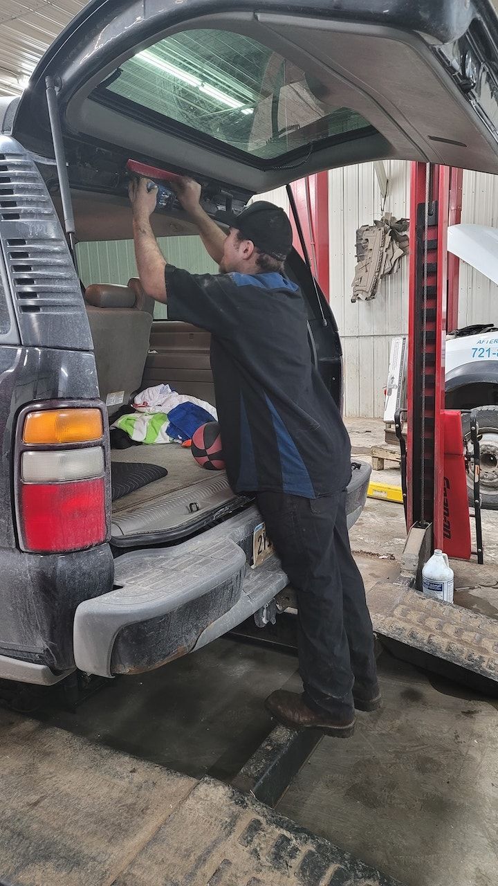 Mechanic working inside the open trunk of an SUV in a service bay | Belly Brothers Auto Tech