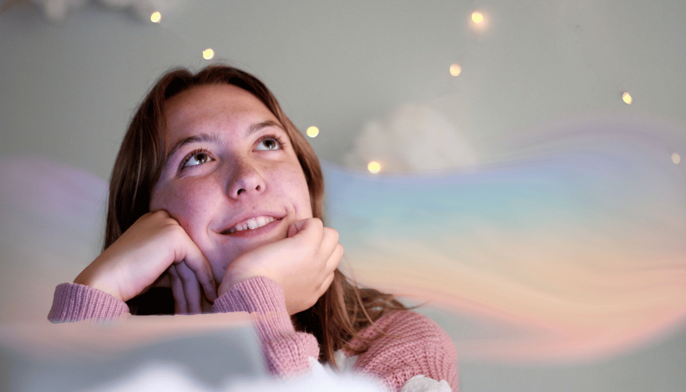 A young woman in a pink sweater is looking up at the sky.