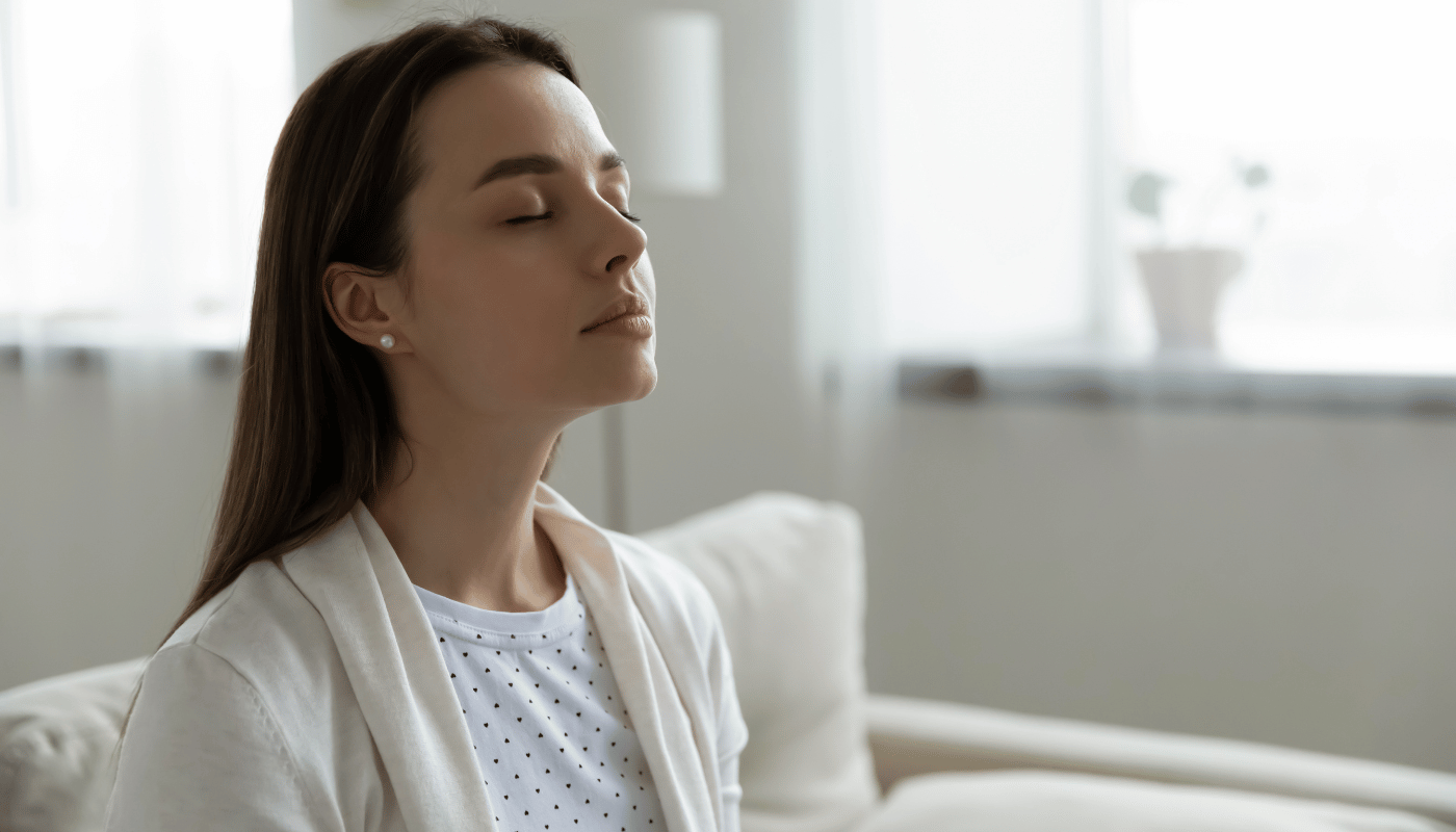 A woman is sitting on a couch with her eyes closed.