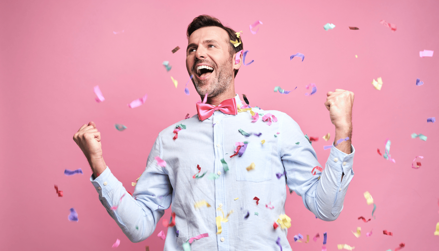 A man in a bow tie is celebrating with confetti falling around him.