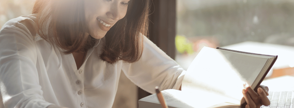 A woman is sitting at a table writing in a notebook.