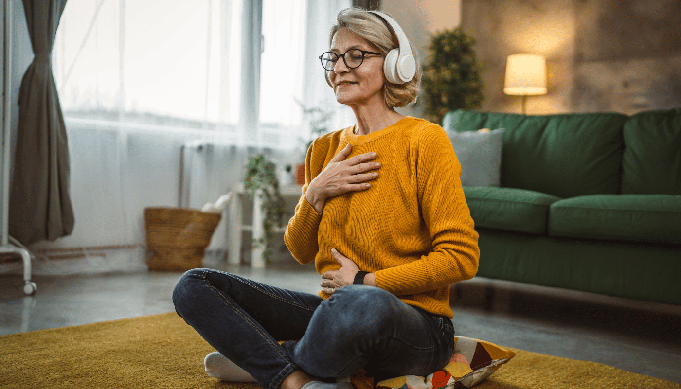 A woman is sitting on the floor wearing headphones and listening to music.