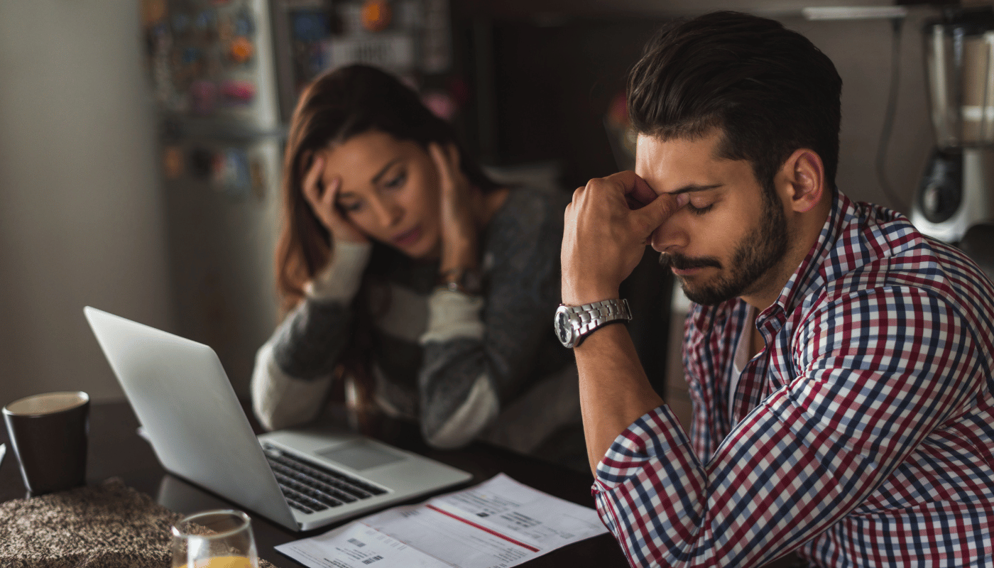 A man and a woman are sitting at a table with a laptop and papers.