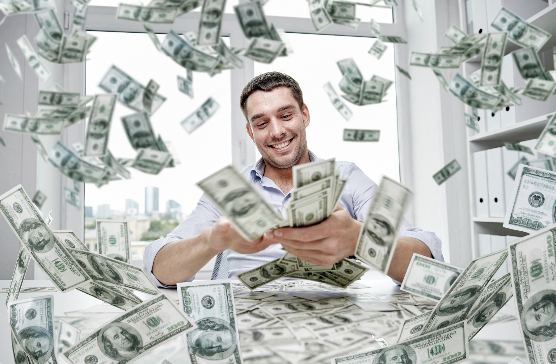 A man is sitting at a table surrounded by money.