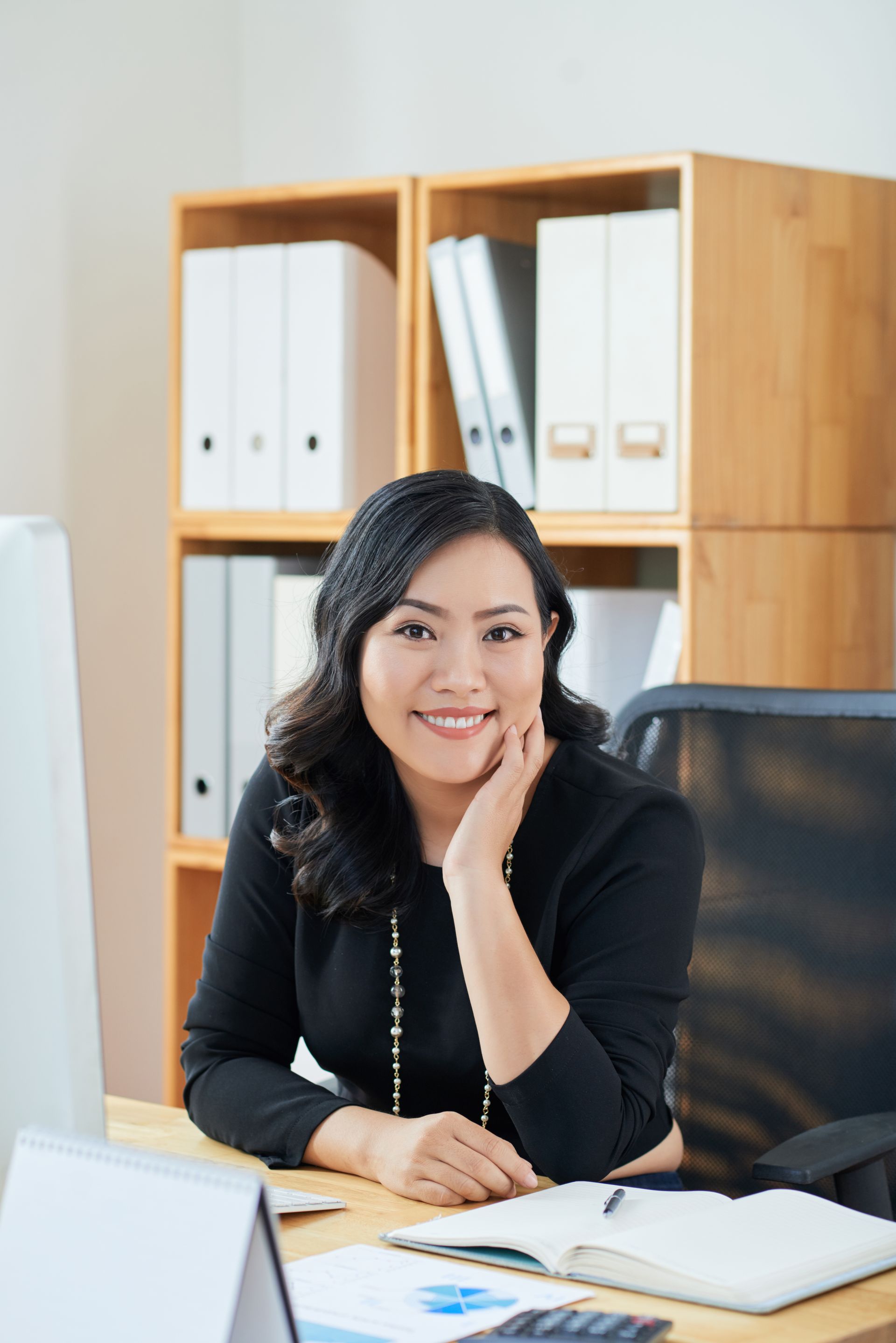 A virtual assistant woman is sitting at a desk in front of a computer.