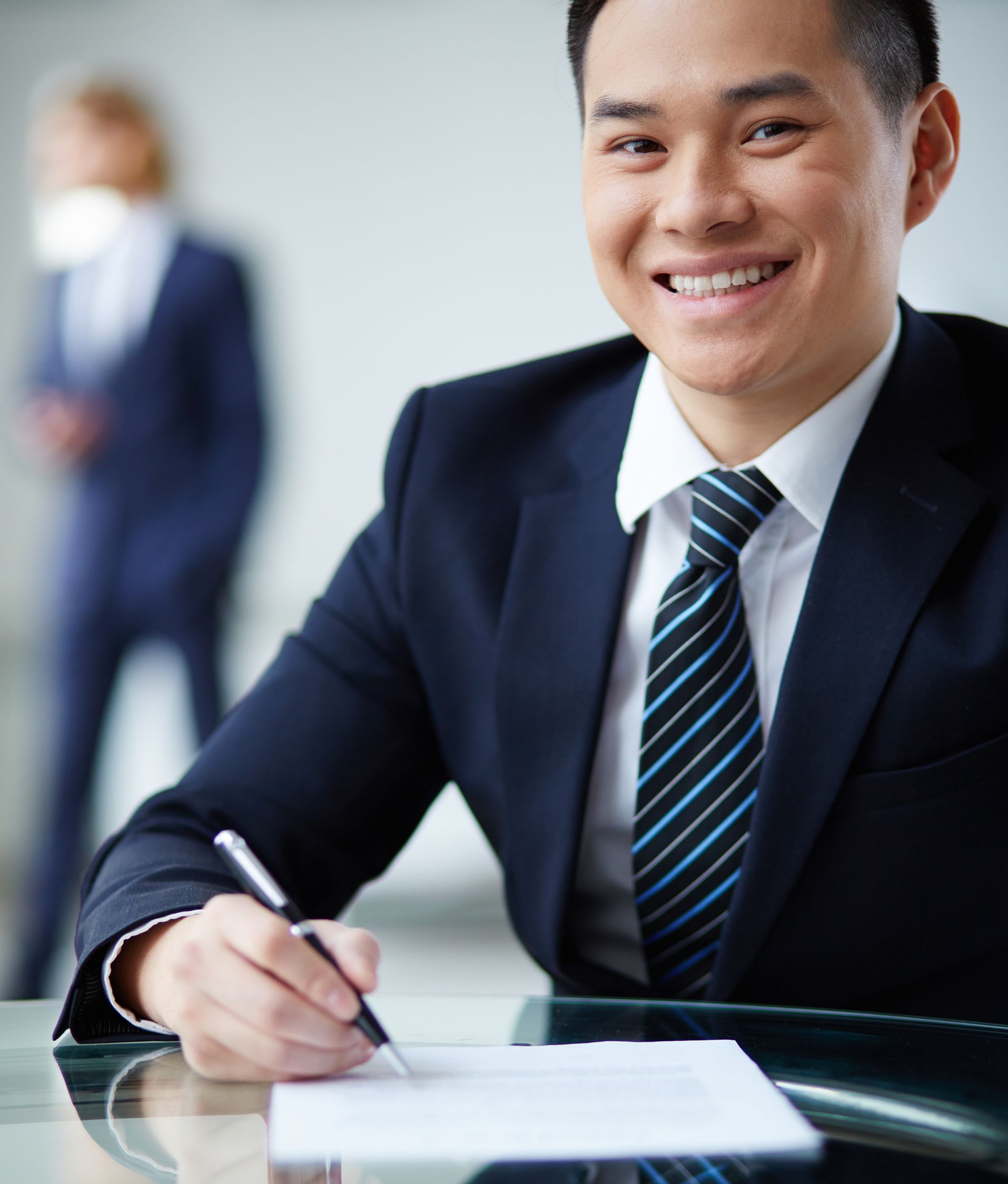 A man in a suit and tie is writing on a piece of paper
