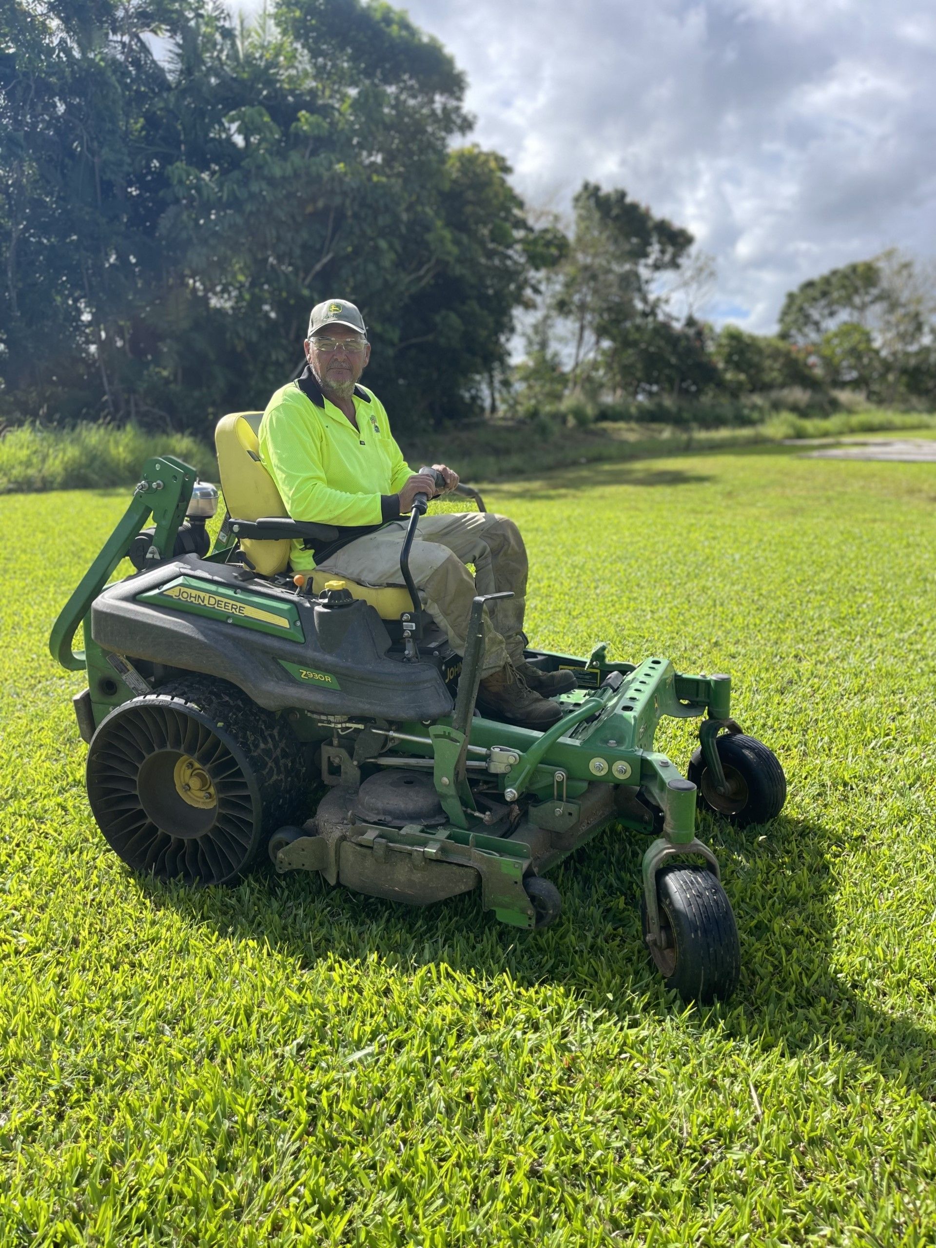 Gardener Cutting Grass With a Green Lawn Mower — Gardeners in Innisfail, QLD