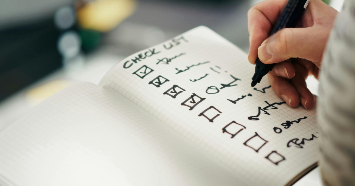 Hand checking items off a paper checklist with a pen