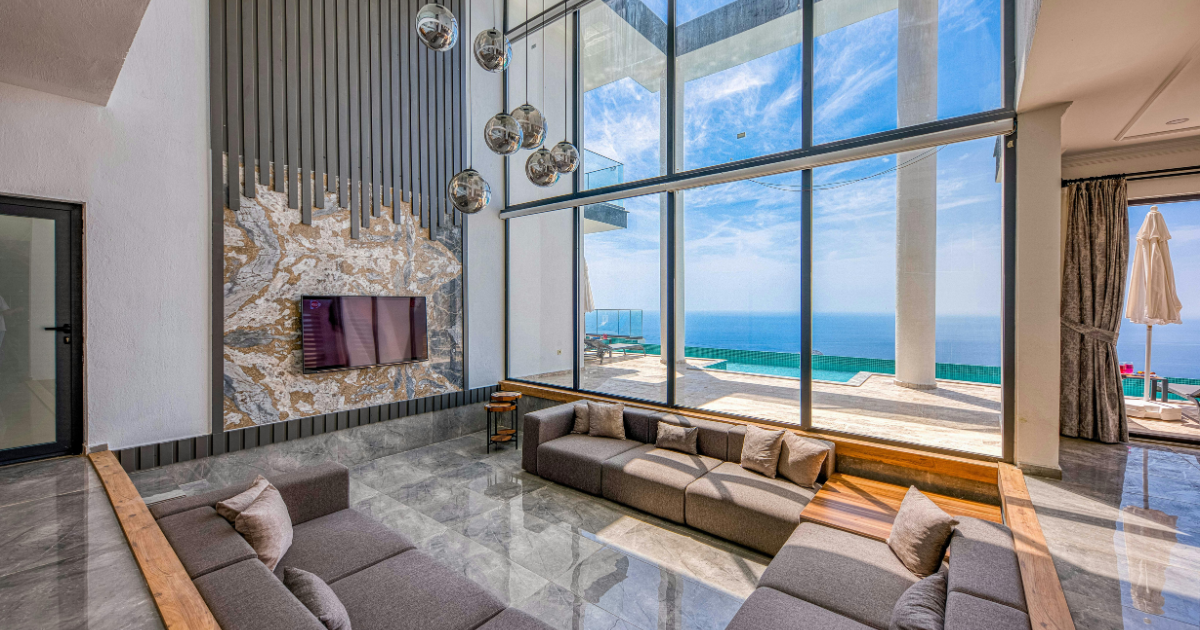 Luxurious oceanfront living room with floor-to-ceiling windows, modern seating, and beach views