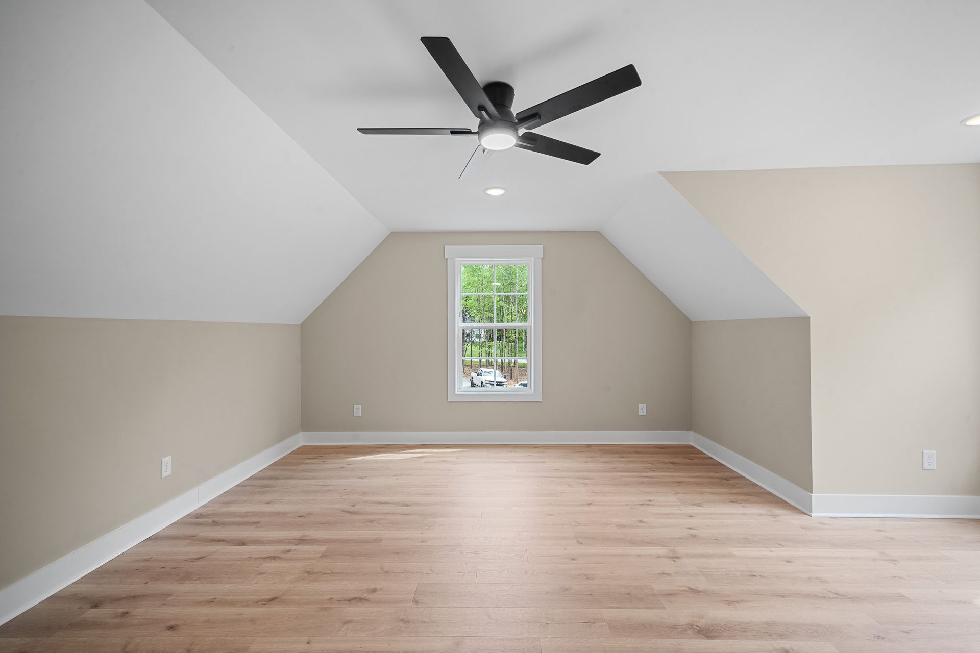 An empty room with a ceiling fan and a window