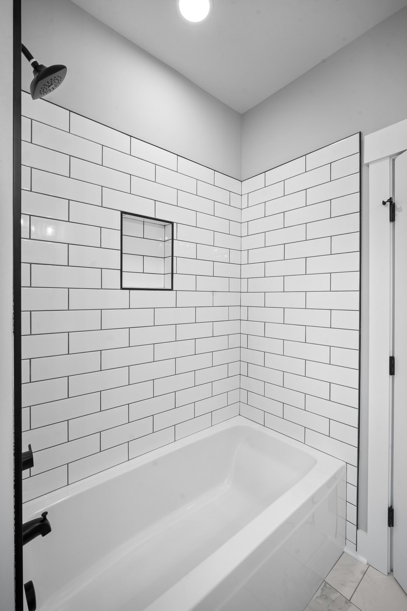 A bathroom with white tiles and a bathtub and shower.